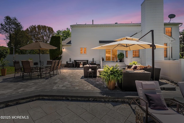 back of property with fence, outdoor dining area, a chimney, an outdoor hangout area, and a patio area
