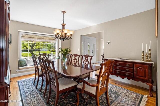 dining room with baseboards, light wood finished floors, and a notable chandelier