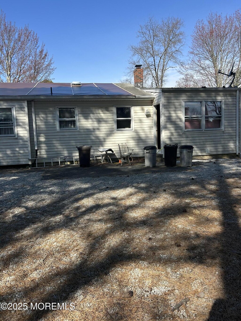 rear view of property with roof mounted solar panels and a chimney