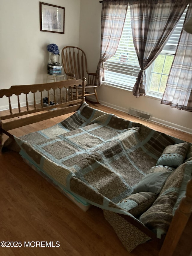 bedroom with baseboards, visible vents, and wood finished floors