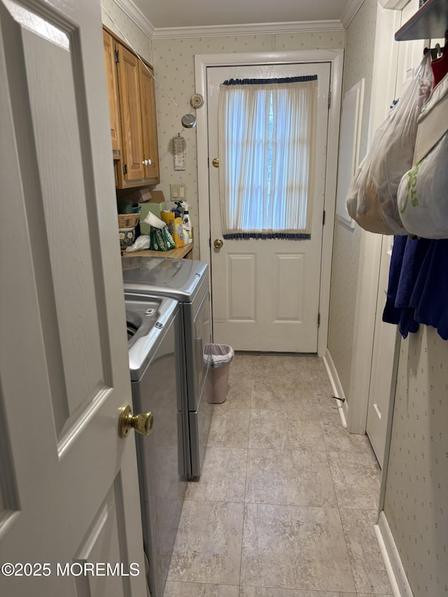 laundry room with ornamental molding, washing machine and clothes dryer, cabinet space, and wallpapered walls