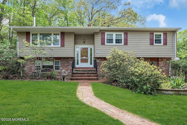 bi-level home featuring entry steps, a front lawn, brick siding, and a chimney
