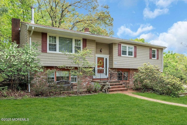 bi-level home featuring a chimney, a front lawn, and brick siding