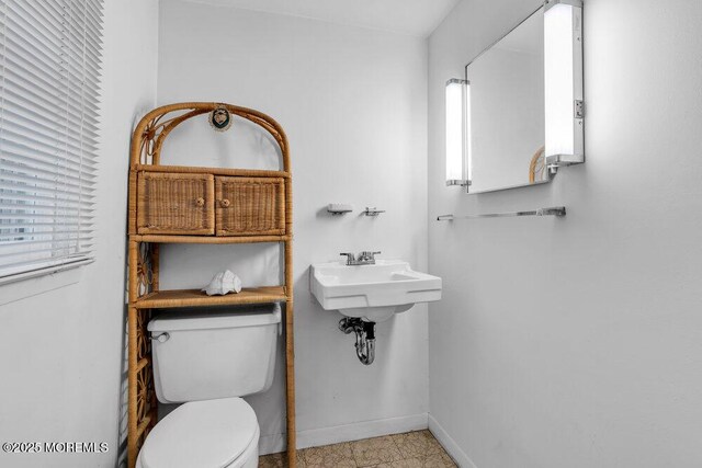 half bath with baseboards and toilet