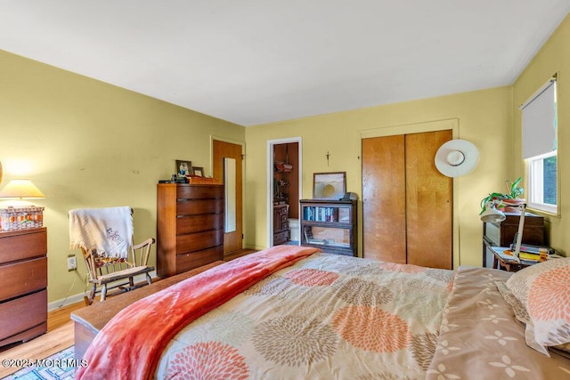 bedroom with a closet, wood finished floors, and baseboards