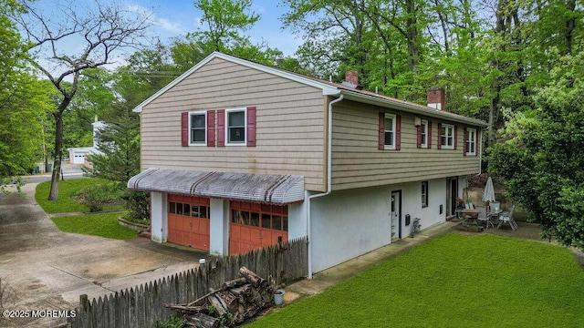 back of house with a chimney, driveway, a garage, and stucco siding