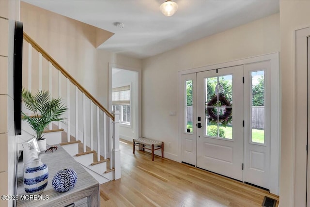 entryway with stairs, visible vents, a healthy amount of sunlight, and light wood finished floors