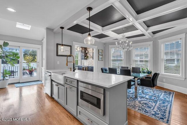 kitchen featuring hanging light fixtures, an inviting chandelier, a sink, stainless steel appliances, and gray cabinetry