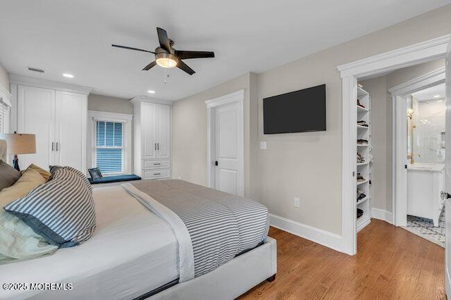 bedroom featuring baseboards, ensuite bathroom, light wood-type flooring, recessed lighting, and a ceiling fan