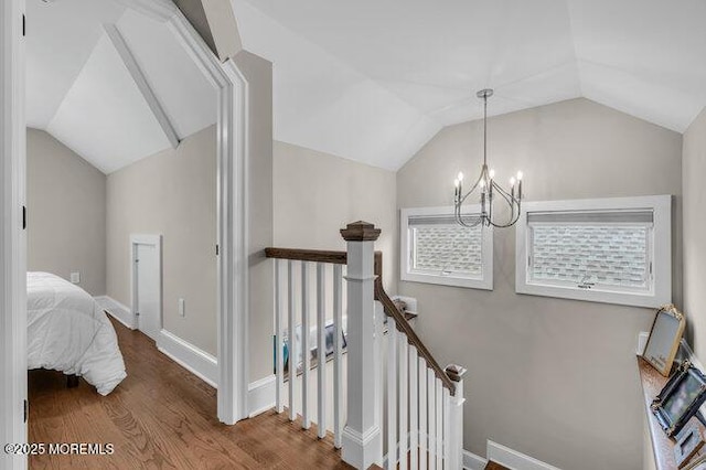 stairs with baseboards, vaulted ceiling, wood finished floors, and a chandelier