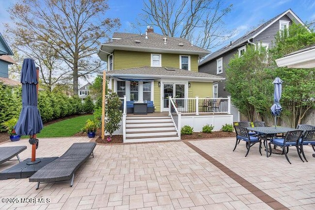 back of property featuring a patio, a chimney, outdoor dining area, and a deck