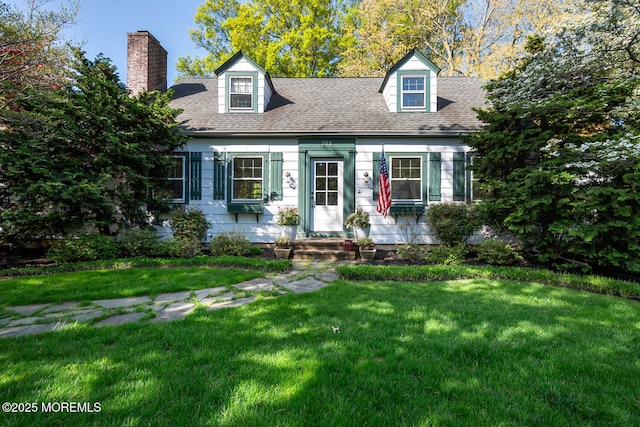 cape cod-style house featuring a shingled roof, a chimney, and a front lawn