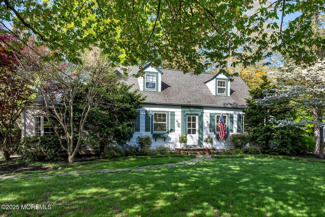new england style home with a front lawn and roof with shingles
