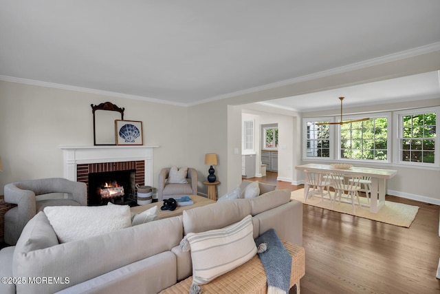 living area featuring crown molding, baseboards, a brick fireplace, and wood finished floors