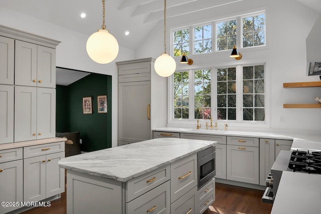 kitchen featuring stainless steel microwave, hanging light fixtures, high vaulted ceiling, and a healthy amount of sunlight