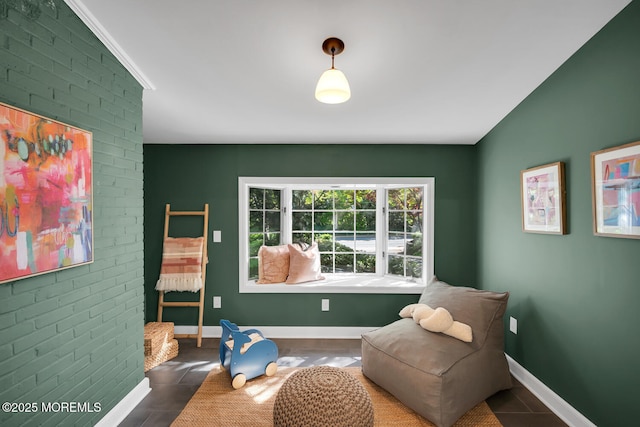 sitting room with baseboards, tile patterned floors, and brick wall