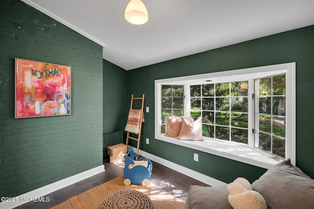 game room with baseboards, vaulted ceiling, and brick wall