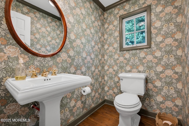 half bath with baseboards, ornamental molding, toilet, and wood finished floors
