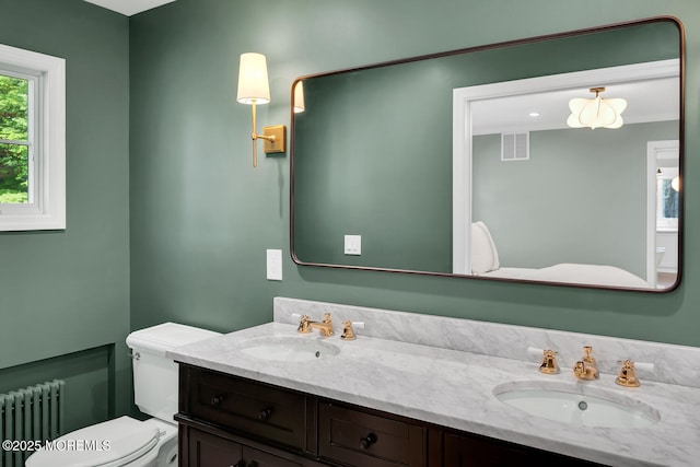 bathroom featuring a sink, radiator heating unit, toilet, and double vanity