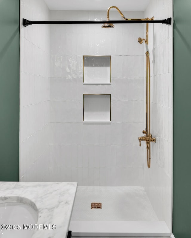bathroom with a tile shower and vanity