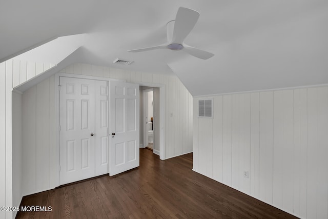 additional living space featuring visible vents, lofted ceiling, and dark wood-type flooring