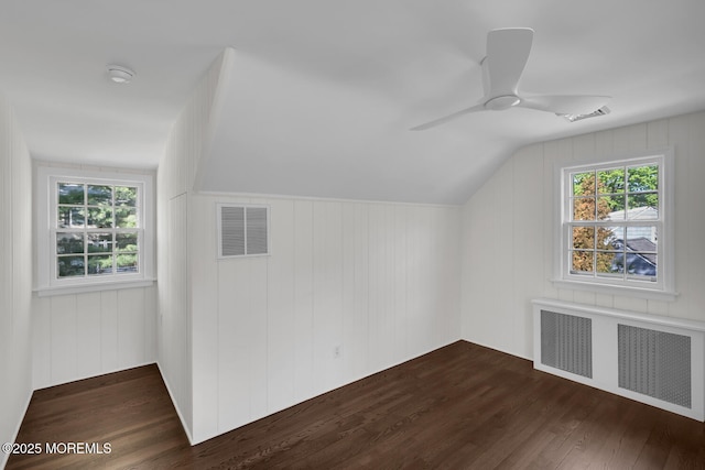 additional living space featuring radiator, a ceiling fan, dark wood finished floors, and visible vents