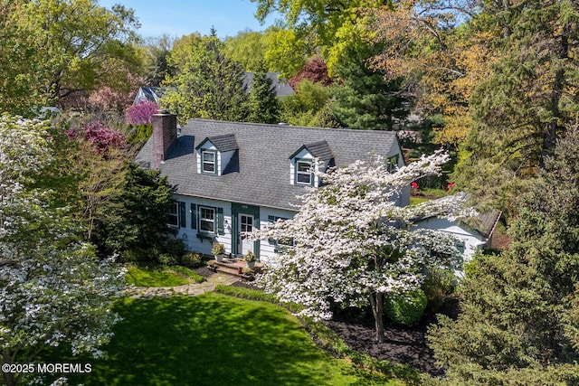 exterior space with a chimney, a shingled roof, and a front lawn