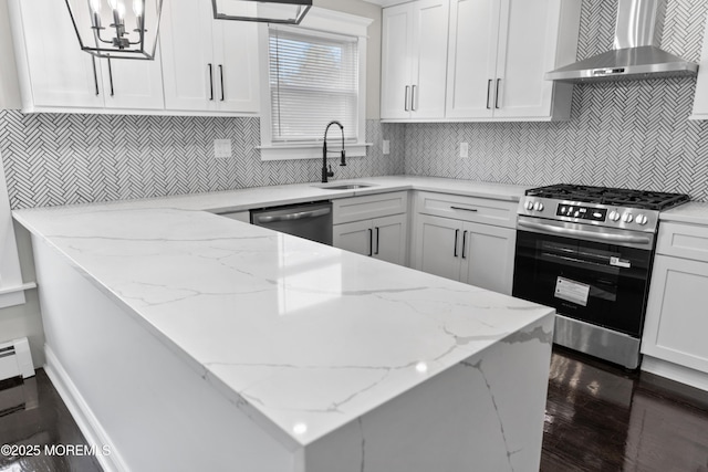 kitchen with wall chimney range hood, white cabinets, appliances with stainless steel finishes, and a sink