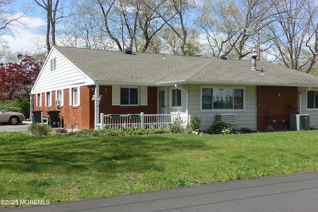 ranch-style home with a shingled roof, brick siding, a front yard, and central AC