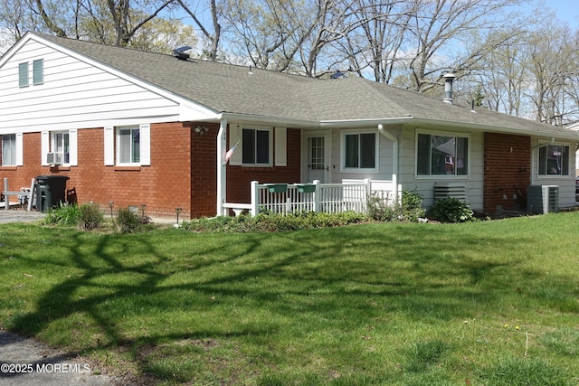 back of property featuring central air condition unit, brick siding, and a lawn