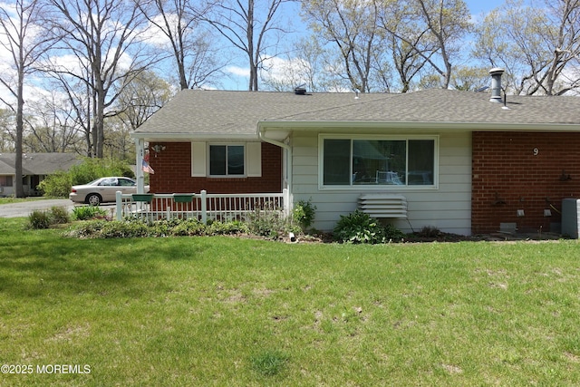 ranch-style home featuring central AC, a shingled roof, brick siding, and a front yard