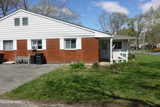 exterior space featuring a yard, cooling unit, and brick siding