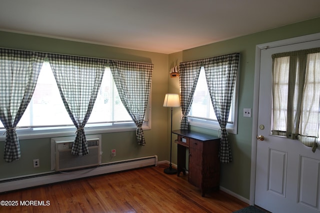 foyer featuring a baseboard radiator, a wall unit AC, plenty of natural light, and wood finished floors