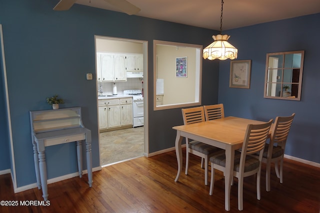 dining area featuring light wood-style flooring, baseboards, and ceiling fan with notable chandelier