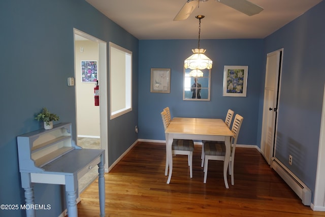 dining space with wood finished floors, baseboards, a baseboard heating unit, and ceiling fan with notable chandelier