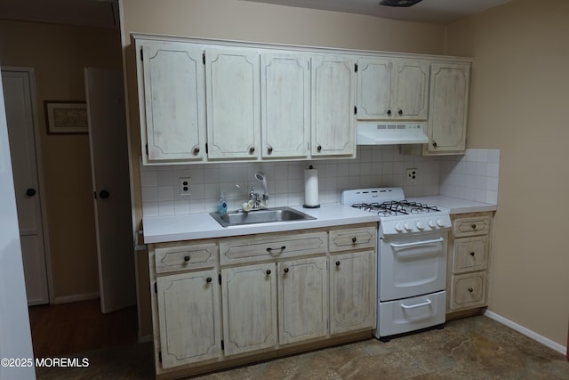 kitchen featuring under cabinet range hood, baseboards, light countertops, tasteful backsplash, and white range with gas cooktop