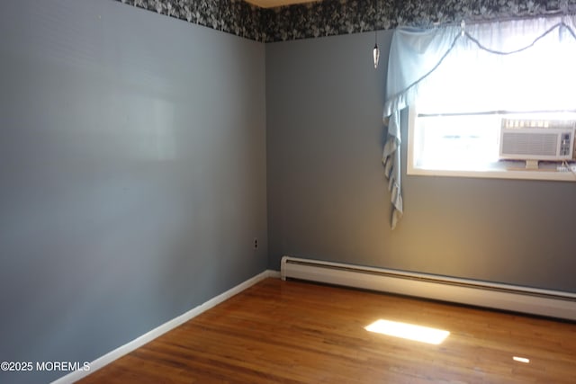 unfurnished room featuring cooling unit, wood finished floors, baseboards, and a baseboard heating unit