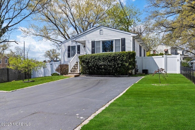 bungalow-style home with fence, driveway, and a front lawn