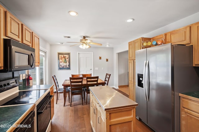 kitchen with visible vents, electric range, black microwave, stainless steel refrigerator with ice dispenser, and a ceiling fan