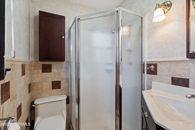 full bathroom featuring wainscoting, a stall shower, toilet, and tile walls