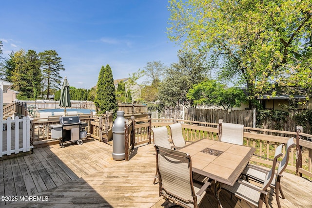 deck with area for grilling, outdoor dining space, and a fenced backyard