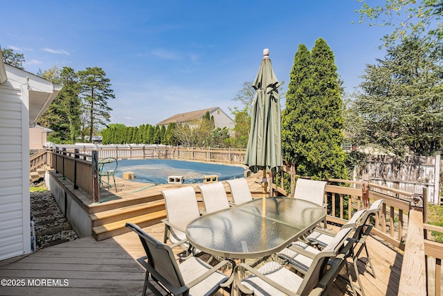 wooden deck with a fenced in pool, a fenced backyard, and outdoor dining space