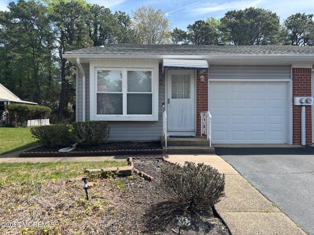 view of front of house featuring driveway, roof with shingles, brick siding, and a garage
