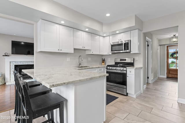 5 Blueberry Path, Howell, NJ 07731 - kitchen featuring stainless steel appliances, a sink, white cabinets, a peninsula, and light stone countertops
