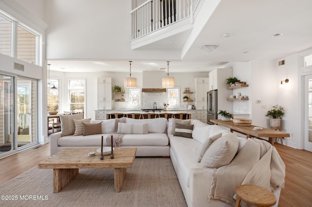 living room featuring visible vents, recessed lighting, light wood-style flooring, and a high ceiling