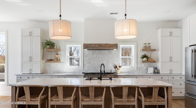 kitchen with high quality fridge, light countertops, open shelves, and backsplash