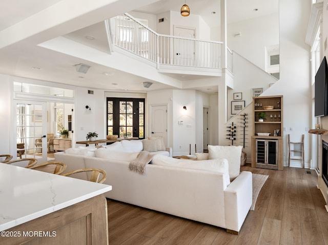 living area featuring a towering ceiling, wine cooler, and hardwood / wood-style floors