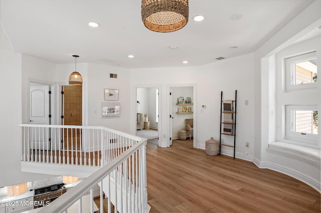 hallway with an upstairs landing, recessed lighting, light wood-style flooring, and baseboards