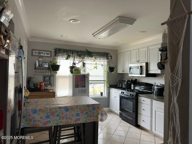 kitchen featuring black gas stove, light tile patterned floors, stainless steel microwave, ornamental molding, and white cabinetry