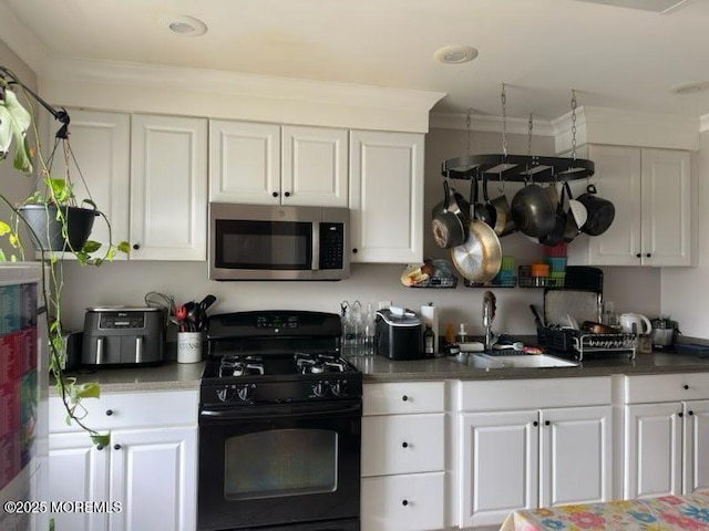 kitchen with a sink, white cabinets, stainless steel microwave, and gas stove